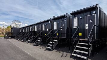 A row of black modular units with numbered doors, each with a staircase leading to the entrance.