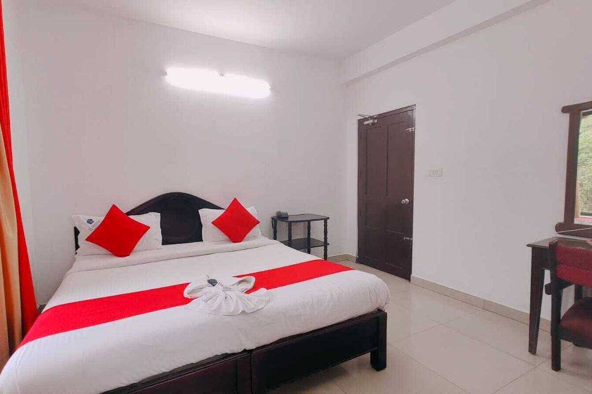 A hotel room with a bed, a desk, and a wardrobe.