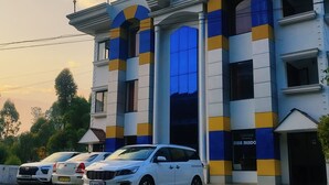 Un edifici d'estil arquitectònic modern, amb grans finestres i un terrat pla. Diversos cotxes estacionats al davant i un camí rural que hi mena.