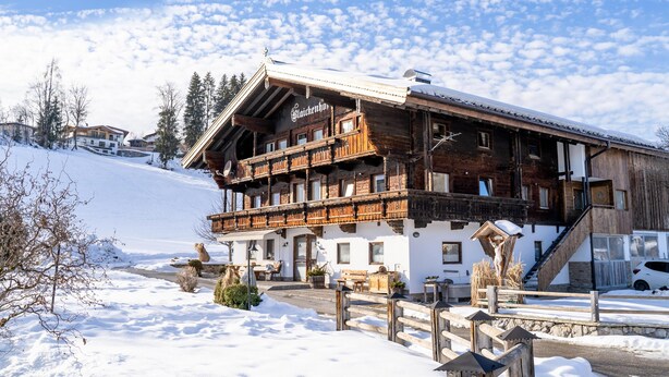 A wooden chalet with a balcony, surrounded by snow-covered ground and trees. - Holiday home a short distance from the ski lift (Hopfgarten im Brixental)