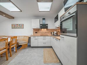 A modern kitchen with skylights, a dining area with a bench, and a painting on the wall.