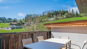 An outdoor patio with a table and chairs, overlooking a green landscape with trees and buildings. - Holiday home a short distance from the ski lift (Hopfgarten im Brixental)