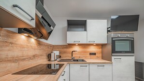 A modern kitchen with wooden countertops, stainless steel appliances, and white cabinetry. - Holiday home a short distance from the ski lift (Hopfgarten im Brixental)