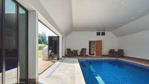 A modern indoor swimming pool with a clear view of the outside garden. - Estate Lodge -  Luxury Cottages (Leominster)