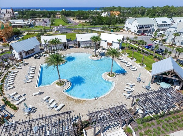 A resort with a central swimming pool, sun loungers, and a view of the ocean.