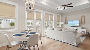 A spacious living room with a dining area, a ceiling fan, and a television.