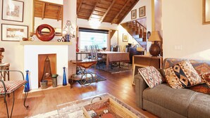 Un vaste salon doté d’une cheminée, de parquets en bois, d’un coin repas et d’un escalier menant à l’étage supérieur.