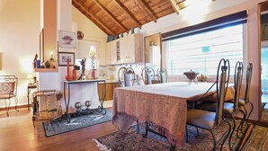 Un coin repas avec une table dressée pour quatre personnes, entourée de chaises à structure métallique. Une nappe à motifs recouvre la table.
