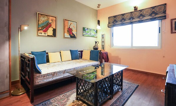 A living room with a sofa, a glass coffee table, and artwork on the walls.