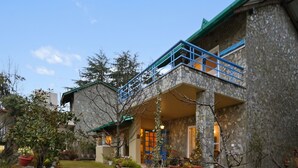 Un bâtiment en pierre doté d’un balcon et agrémenté de nombreuses plantes en pot.