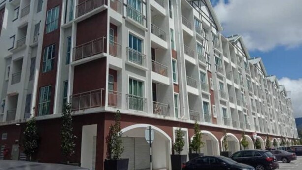 A multi-story residential building with balconies, a parking area, and a clear sky.