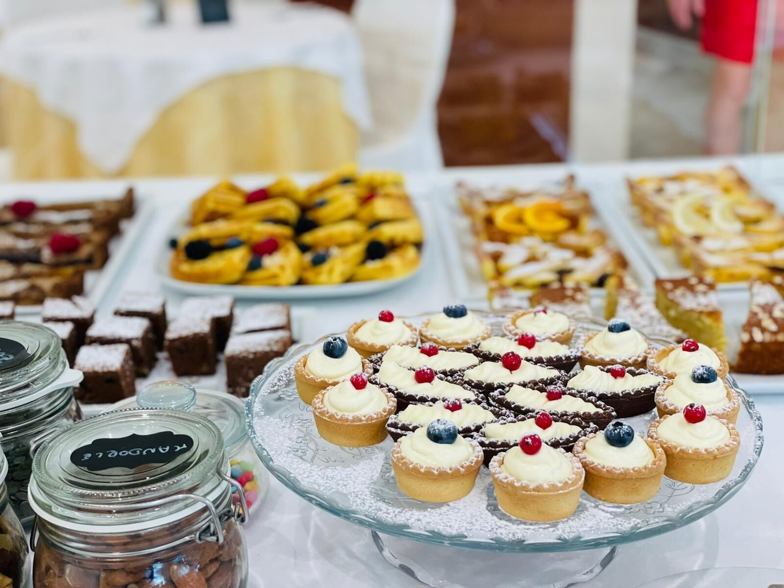 A buffet table with various desserts including cupcakes with berries, pastries, and brownies.