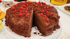 Un gâteau au chocolat garni de cerises, présenté sur une assiette blanche.