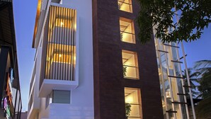 Un bâtiment moderne doté d’une façade en verre, un restaurant appelé « Nivedya » situé au rez-de-chaussée, et une entrée bien éclairée.