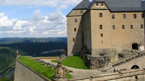 A large castle with a prominent tower, a fortified wall, and a scenic view of the surrounding landscape. - Ferienwohnung in Struppen (Struppen)