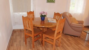 Uma mesa de jantar de madeira com seis cadeiras, um vaso com flores e uma revista sobre a mesa.