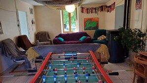 Et værelse med et fodboldbord, en lilla sofa, en grøn lænestol og et fjernsyn.