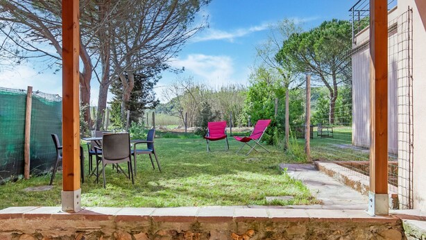 A patio area with outdoor furniture, a stone wall, and a view of the surrounding landscape. - Belvilla by OYO Casa Cecina (Riparbella)