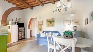 A cozy kitchen with a microwave, refrigerator, and a dining area with a table and chairs. - Belvilla by OYO Casa Cecina (Riparbella)