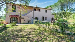 A two-story house with a sloped roof, a small balcony, and a fenced garden area. - Belvilla by OYO Casa Cecina (Riparbella)