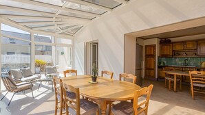 Un comedor amplio con una mesa y sillas de madera, techo de vidrio y vistas al exterior.