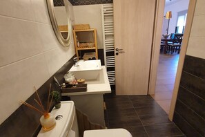 A compact bathroom with a white sink, mirror, and a towel rack. - Apartment in Loutra Elenis with Garden (Loutra Elenis)