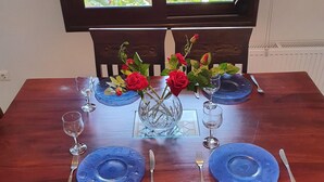 Een eettafel gedekt met blauwe borden, bestek en een vaas met rode rozen.