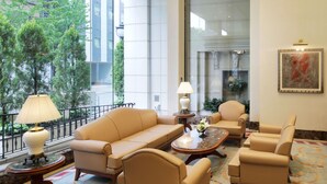 A modern hotel lobby with a large window, a beige sofa set, a coffee table, and a patterned carpet. - KOKO HOTEL Nagoya Sakae (Nagoya)