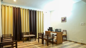 Um quarto com escrivaninha de madeira, duas cadeiras, um computador e uma impressora.