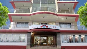 Un hotel de varios pisos con una entrada destacada, balcones y cielo despejado.