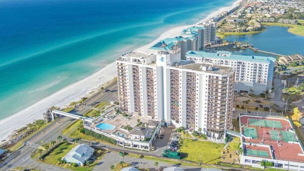 Un hôtel de grande hauteur doté de nombreux balcons donnant sur une plage et une marina.