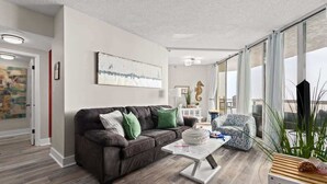 Un salon moderne avec un canapé marron foncé, un fauteuil à motifs et une table basse blanche.
