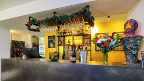 A bar area with a counter, bottles, glasses, and a decorative sculpture. - Das Edlinger (Salzburg)