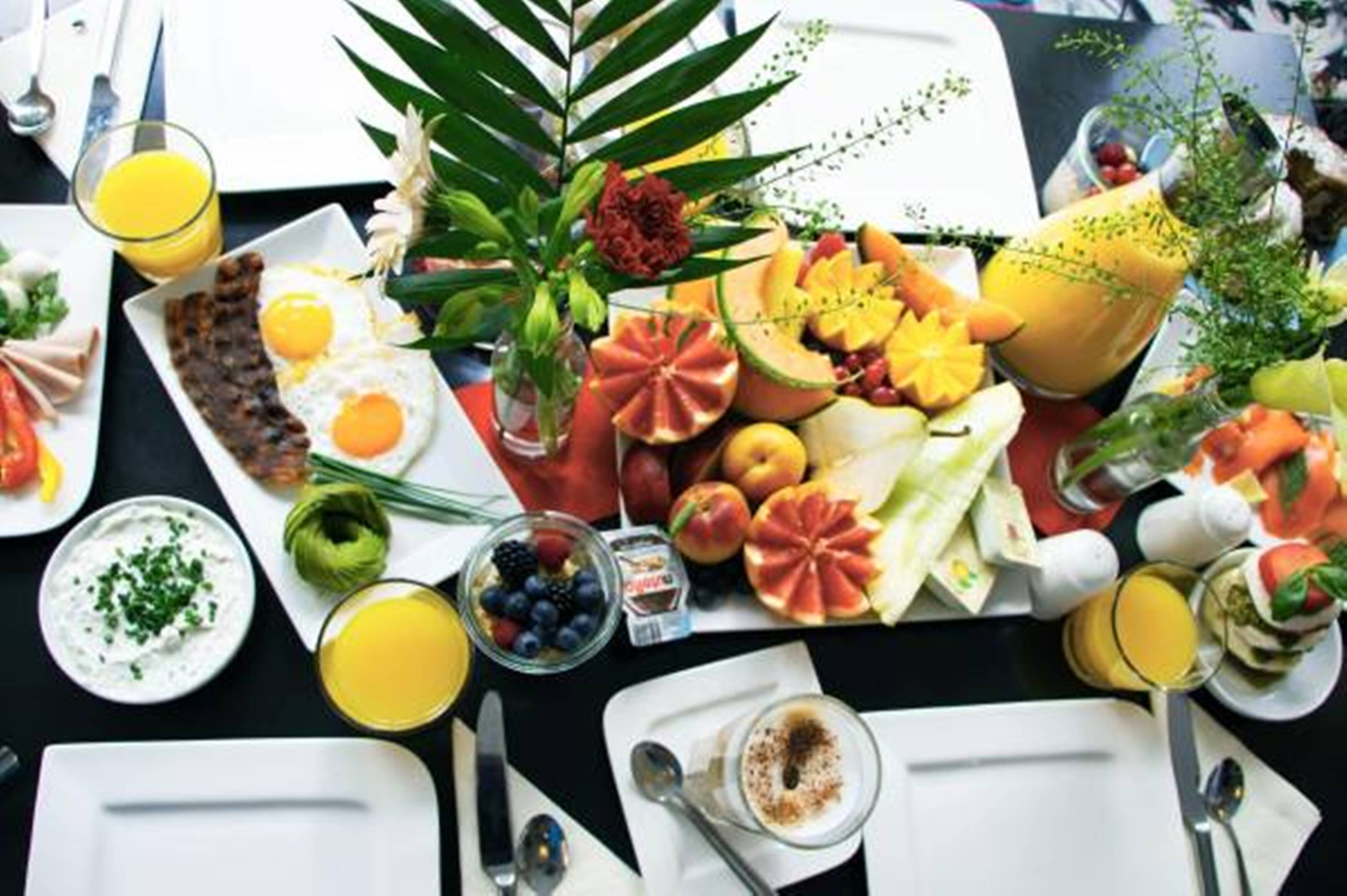 Una colazione con frutta, verdura e bevande varie disposte su un tavolo.