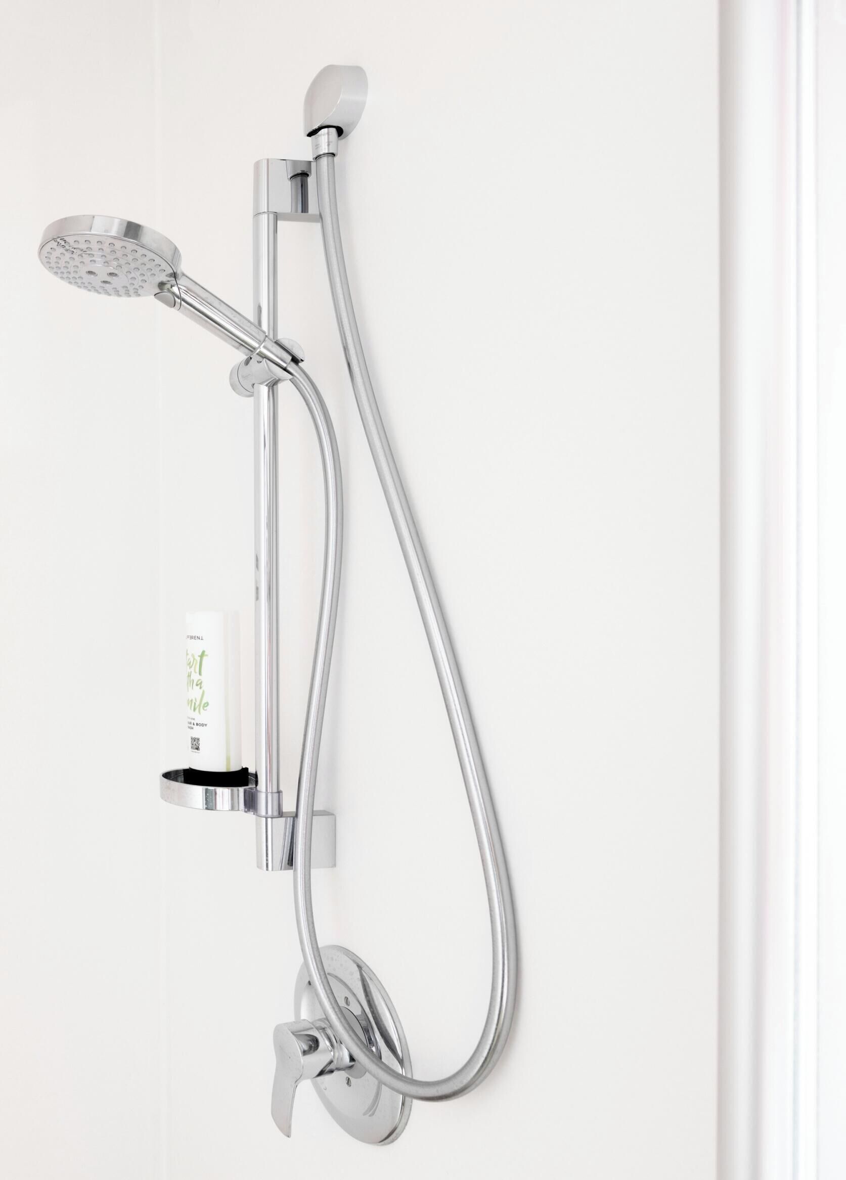 A wall-mounted shower with a handheld showerhead and a handheld shower attachment.