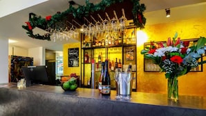 A bar area with a counter, various bottles, a decorative wreath, and a flower arrangement. - Das Edlinger (Salzburg)