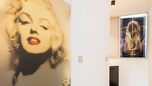 A hallway with a large portrait mural on the wall, a door, and a window with blinds. - Das Edlinger (Salzburg)
