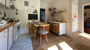 Een keuken met houten kastjes, een eettafel, stoelen en een hangende lamp.