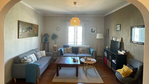 Een woonkamer met een bank, een salontafel, een lamp en een televisie.