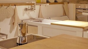 Una cocina moderna con encimera de madera, pileta de acero inoxidable, utensilios colgantes e iluminación colgante.