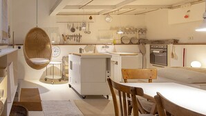 Una cocina moderna con una silla colgante de mimbre, una pequeña mesa de comedor y una silla de madera.