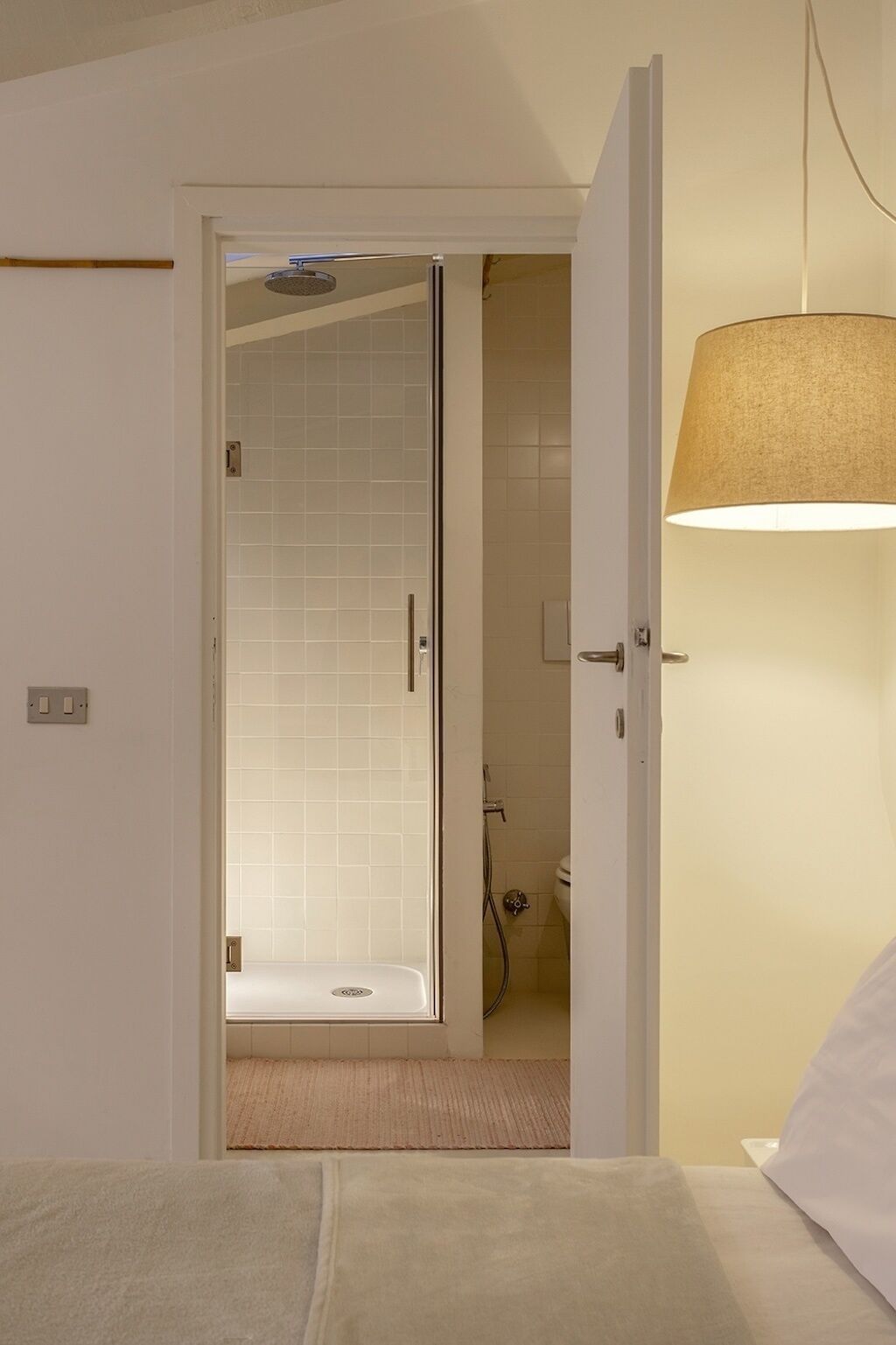 A hotel room with a shower area, a bed, and a lamp.