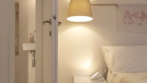 Un dormitorio con cama, mesita de noche, lámpara, alfombra y puerta que da a un baño.