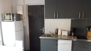 Ett kompakt kök med mikrovågsugn, diskho och diskmaskin. Det finns en liten matplats med ett bord och stolar.