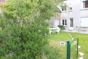 A fenced outdoor area with a number sign, a grassy lawn, and a building with windows and doors in the background.