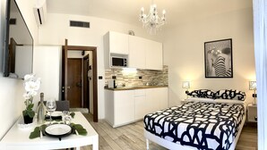 A modern hotel room with a dining area, kitchenette, and a large bed with a patterned bedspread. - LEONARDO & DAVIDE APARTMENT FLORENCE, FREE WI-FI (Firenze)