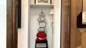 A hallway with a wooden door frame, a black chair, a shelf with a framed picture, and a hanging birdcage. - LEONARDO & DAVIDE APARTMENT FLORENCE, FREE WI-FI (Firenze)