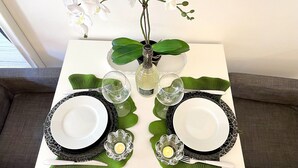 A dining table set with two plates, cutlery, and a vase with white flowers. - LEONARDO & DAVIDE APARTMENT FLORENCE, FREE WI-FI (Firenze)