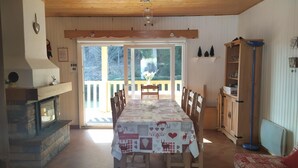 Un coin repas avec une table dressée pour quatre personnes, un buffet en bois et une cheminée.