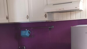 Une cuisine avec des meubles blancs, un plan de travail de couleur violette, une cuisinière et un réfrigérateur.